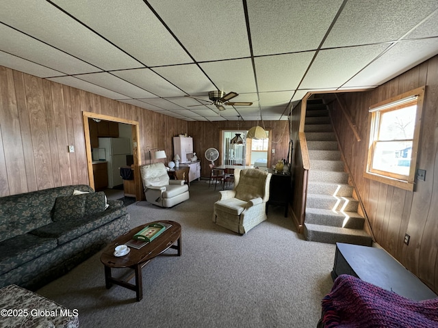 113 Forest Ave, Caroga, NY 12032 - carpeted living room featuring wooden walls, ceiling fan, stairway, and a paneled ceiling
