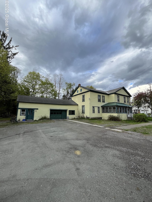 view of front facade with an attached garage, a chimney, and aphalt driveway