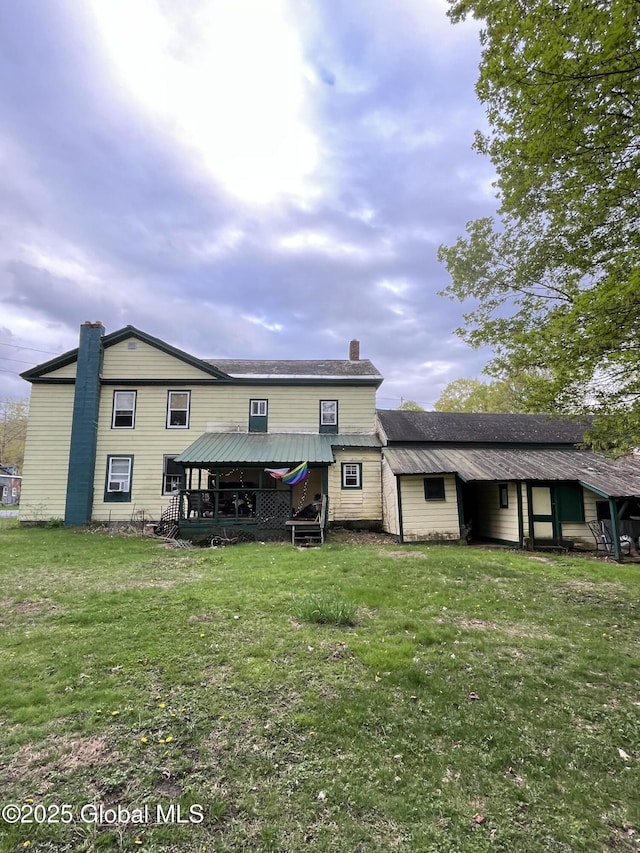 back of property with a yard and a chimney