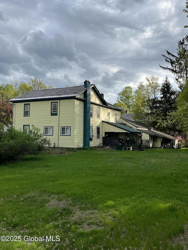 back of house with a yard and a chimney