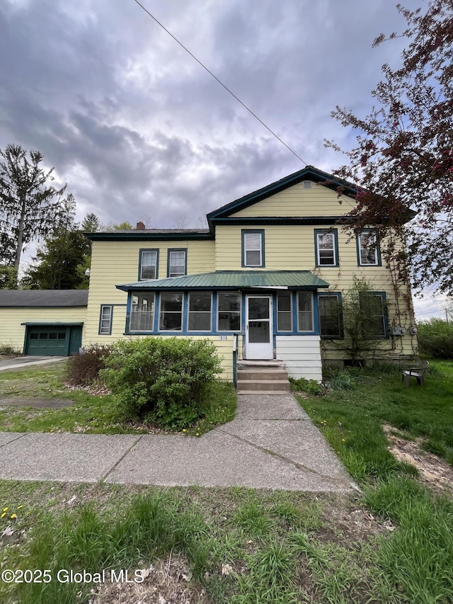 view of front of house featuring a chimney, a sunroom, and a garage