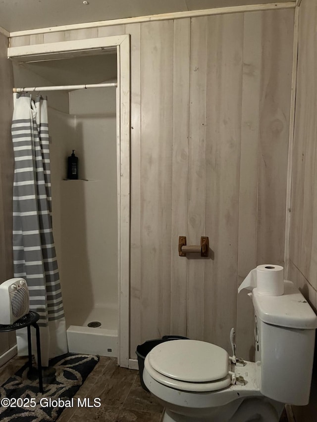 full bath featuring wood walls, a stall shower, and toilet