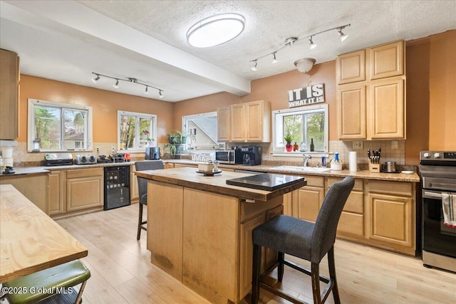 209 Lake Ave, Lake Luzerne, NY 12846 - kitchen featuring wine cooler, appliances with stainless steel finishes, a kitchen breakfast bar, light brown cabinets, and a textured ceiling