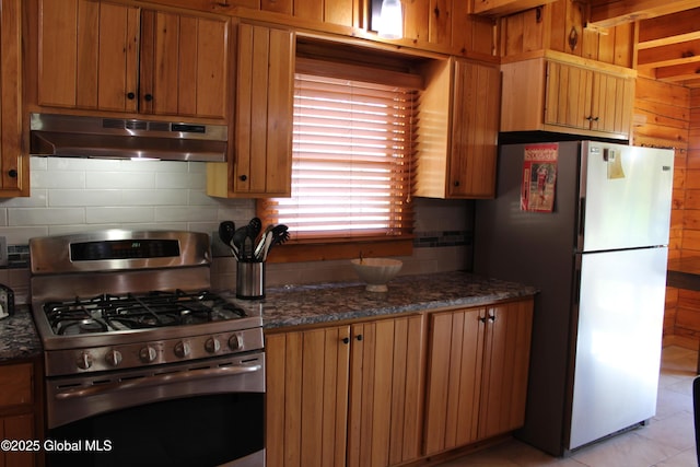 127 Fording Rd, Esperance, NY 12066 - kitchen featuring decorative backsplash, stainless steel gas stove, freestanding refrigerator, dark stone counters, and under cabinet range hood