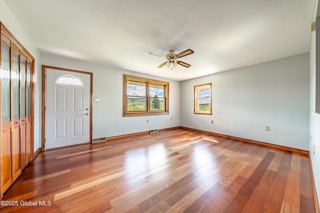 foyer featuring a ceiling fan, baseboards, light wood-type flooring, and visible vents