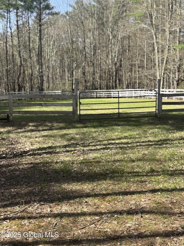 view of community with a lawn, a rural view, and fence