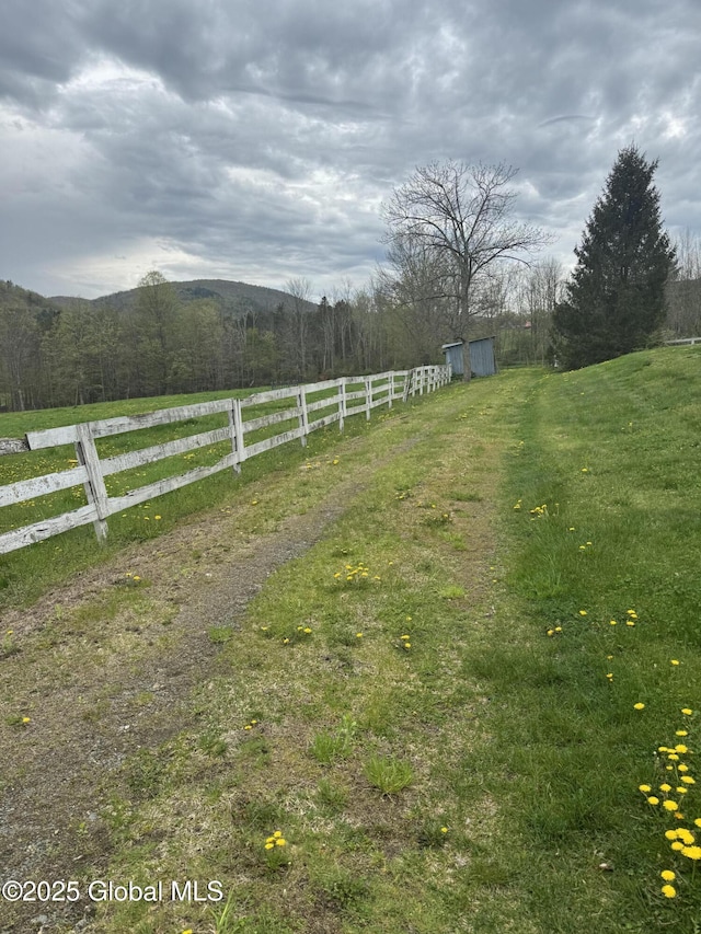 view of yard with a rural view, fence, and an outdoor structure