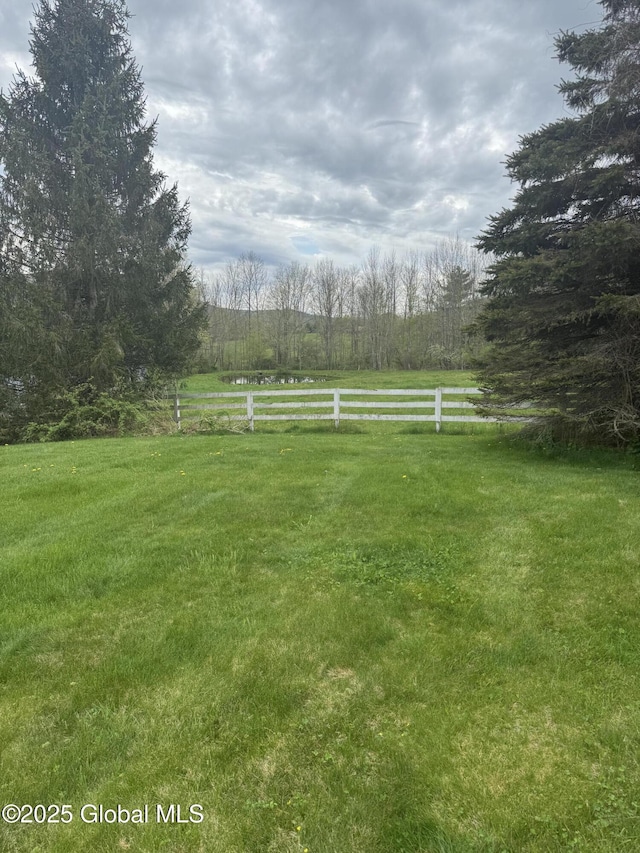 view of yard with fence and a rural view