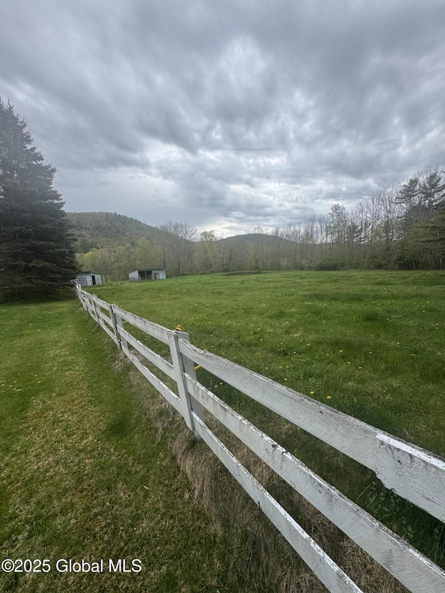 view of yard with a view of trees, fence, and a rural view