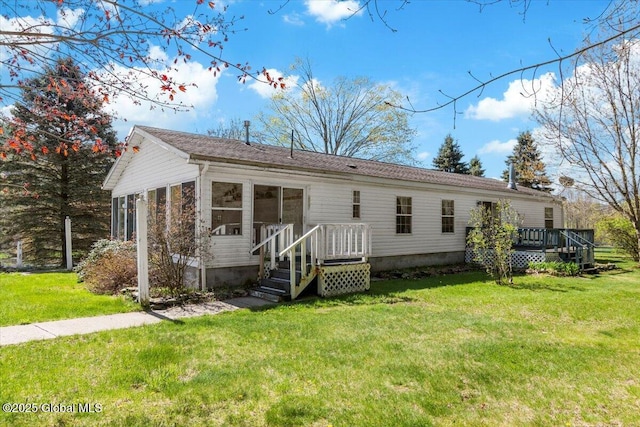 back of house featuring a sunroom, a wooden deck, and a yard