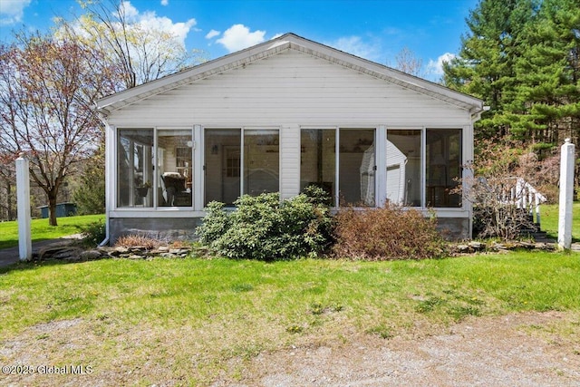 back of house featuring a sunroom and a lawn