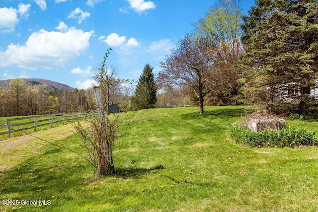 view of yard featuring a rural view, fence, and a mountain view