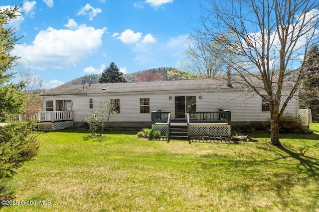 back of house with a yard and a deck with mountain view