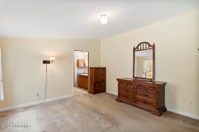 bedroom with baseboards, ensuite bathroom, and light carpet