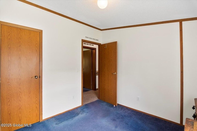 unfurnished bedroom with ornamental molding, dark carpet, a textured ceiling, and visible vents