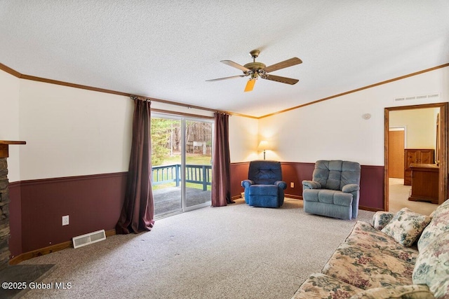 living room featuring visible vents, crown molding, wainscoting, and carpet floors