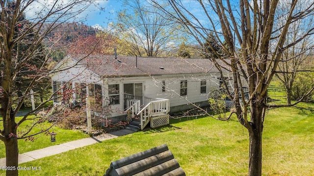 back of house featuring a lawn and a shingled roof