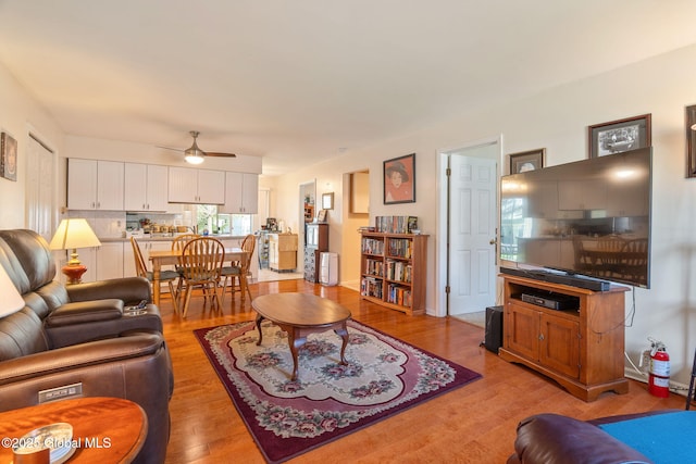 living area featuring light wood-style flooring and ceiling fan