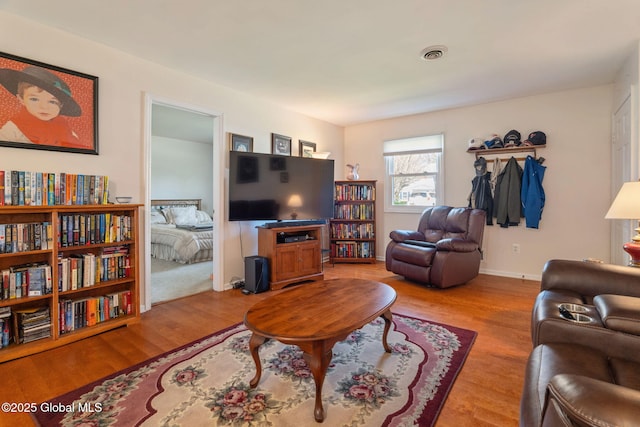 living room with baseboards, light wood finished floors, and visible vents