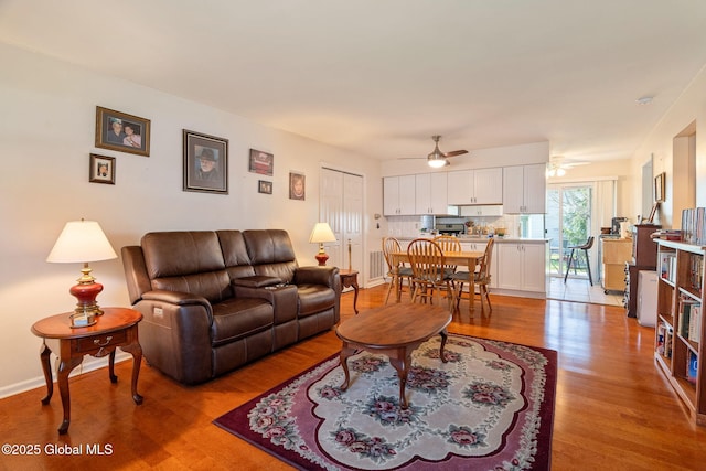 living area featuring a ceiling fan, baseboards, and wood finished floors