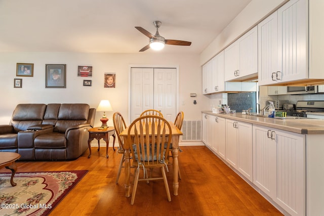 dining space with a ceiling fan, wood finished floors, and visible vents