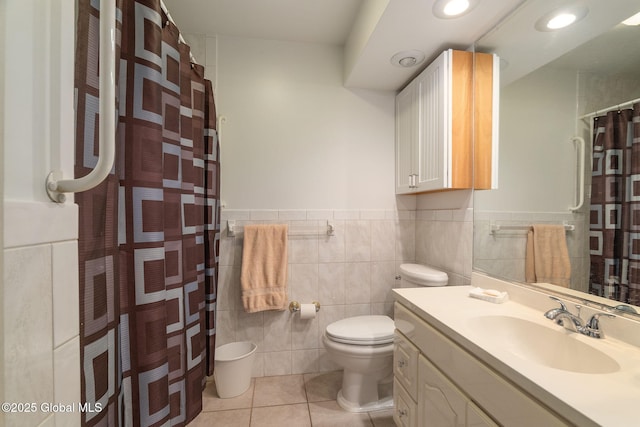 bathroom with wainscoting, tile patterned flooring, vanity, toilet, and tile walls