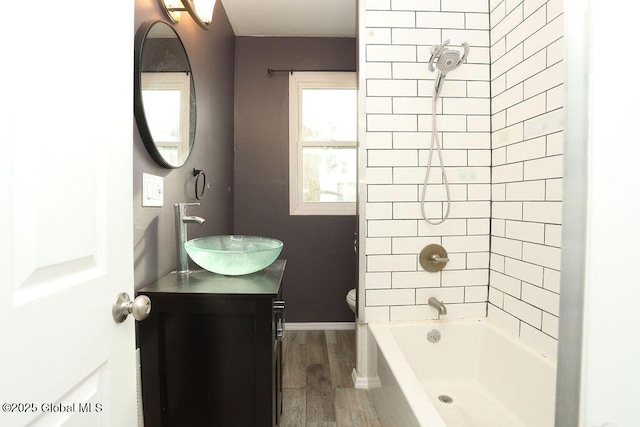 full bath featuring wood finished floors, toilet, vanity, shower / bathtub combination, and baseboards