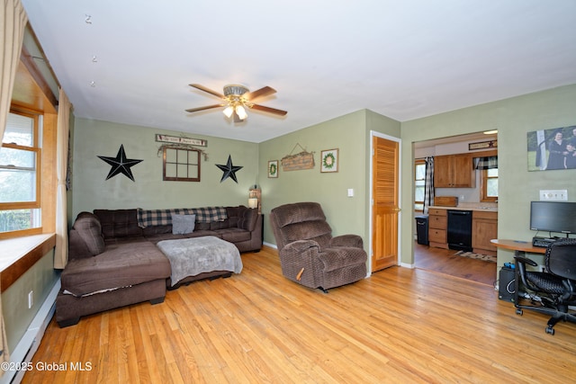 living area featuring light wood-style floors, baseboard heating, and a wealth of natural light