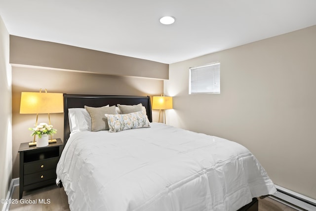 bedroom with wood finished floors and a baseboard heating unit