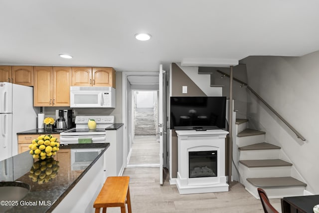 kitchen featuring dark stone counters, recessed lighting, light wood-type flooring, and white appliances