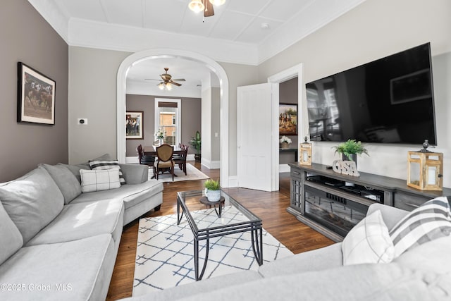 living room with arched walkways, crown molding, ceiling fan, and wood finished floors