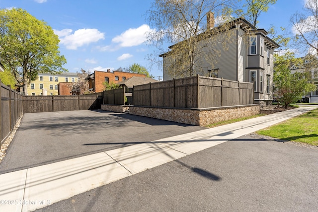 view of side of home featuring fence private yard, a chimney, and a residential view