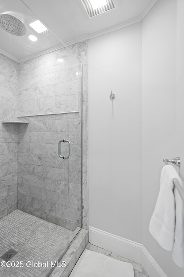 bathroom with marble finish floor, visible vents, crown molding, a shower stall, and baseboards