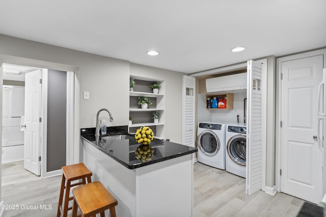 clothes washing area featuring recessed lighting, a sink, washing machine and clothes dryer, laundry area, and light wood-type flooring