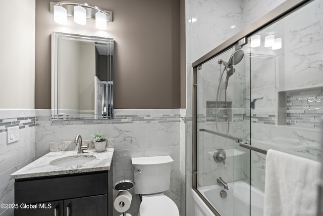 full bathroom featuring tile walls, a wainscoted wall, and shower / bath combination with glass door