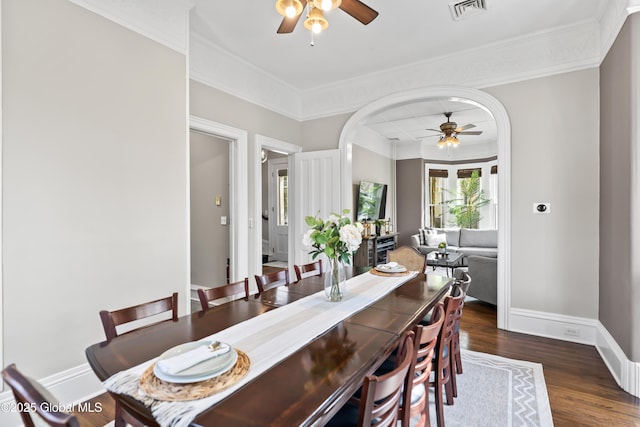 dining room featuring wood finished floors, visible vents, baseboards, ceiling fan, and arched walkways