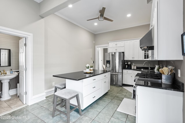 kitchen featuring a breakfast bar area, a sink, dark countertops, stainless steel refrigerator with ice dispenser, and ceiling fan
