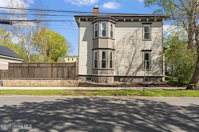 view of side of home featuring fence and a chimney