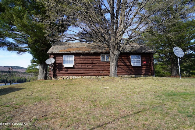 exterior space featuring a mountain view, a yard, and log siding