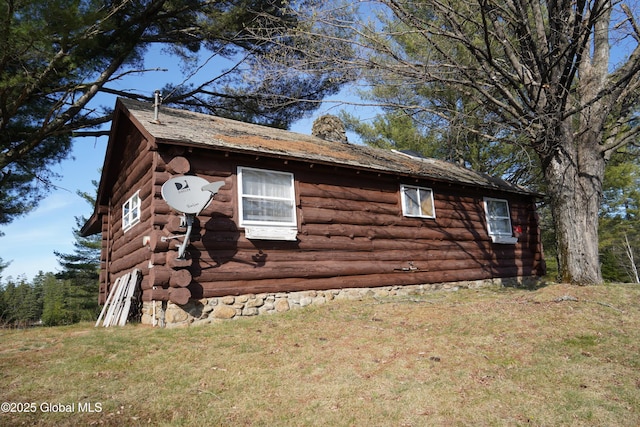 view of side of property with a lawn, a chimney, and log siding