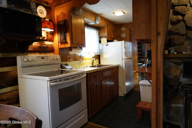 kitchen with white appliances, wooden walls, brown cabinets, and a sink