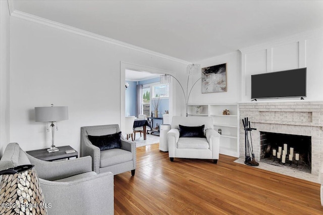 living room with ornamental molding, a brick fireplace, and wood finished floors