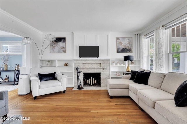 living area featuring ornamental molding, a fireplace, and light wood-type flooring