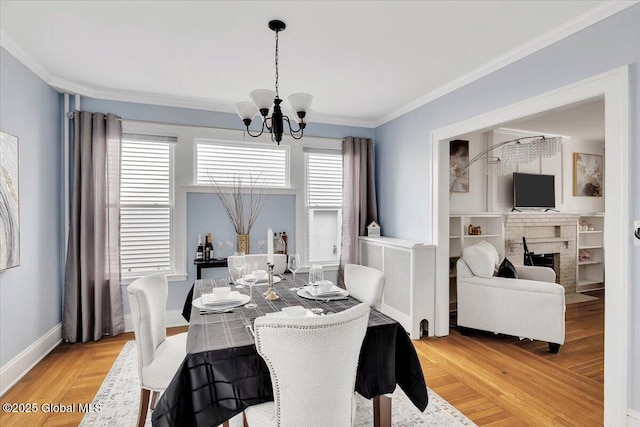 dining space featuring light wood-style flooring, baseboards, ornamental molding, an inviting chandelier, and a brick fireplace