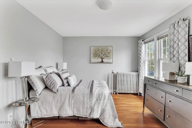 bedroom featuring wood finished floors and radiator heating unit
