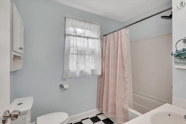 bathroom featuring a sink, toilet, tile patterned floors, shower / bath combination with curtain, and baseboards