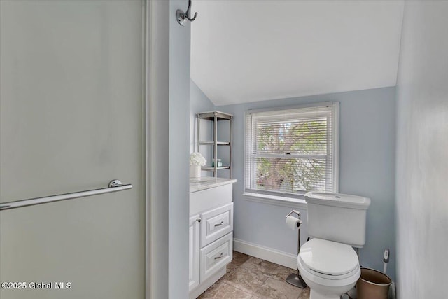 bathroom with vanity, toilet, baseboards, and lofted ceiling