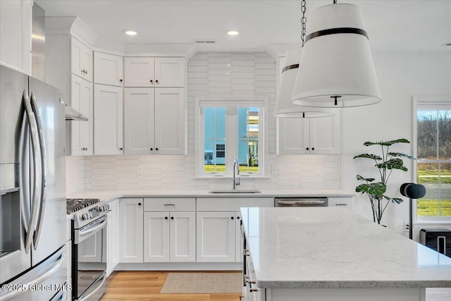 53 Wardley Cir, Colonie, NY 12047 - kitchen with stainless steel appliances, a sink, a center island, white cabinetry, and light stone counters