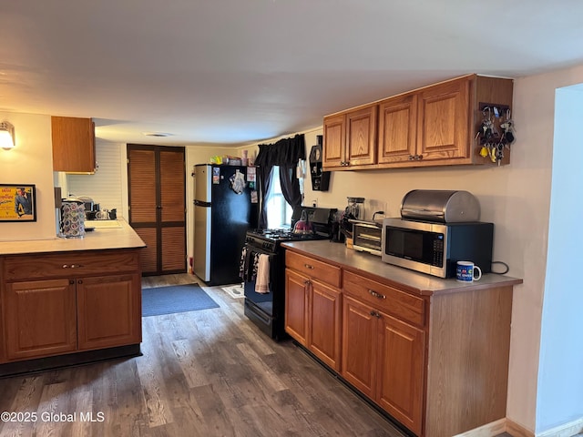 kitchen featuring brown cabinetry, light countertops, dark wood finished floors, and appliances with stainless steel finishes