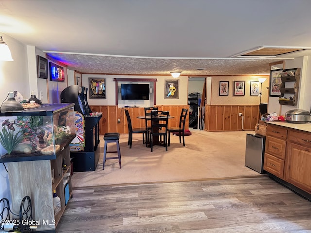 dining room featuring wooden walls, a wainscoted wall, and light wood-style floors